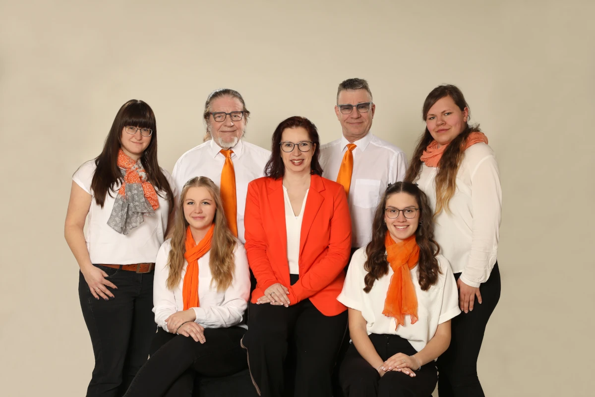 Gruppenfoto eines Teams in Businesskleidung mit orangefarbenen Accessoires